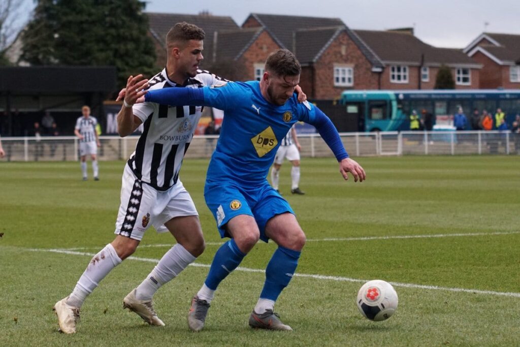 Two footballers battle for a ball