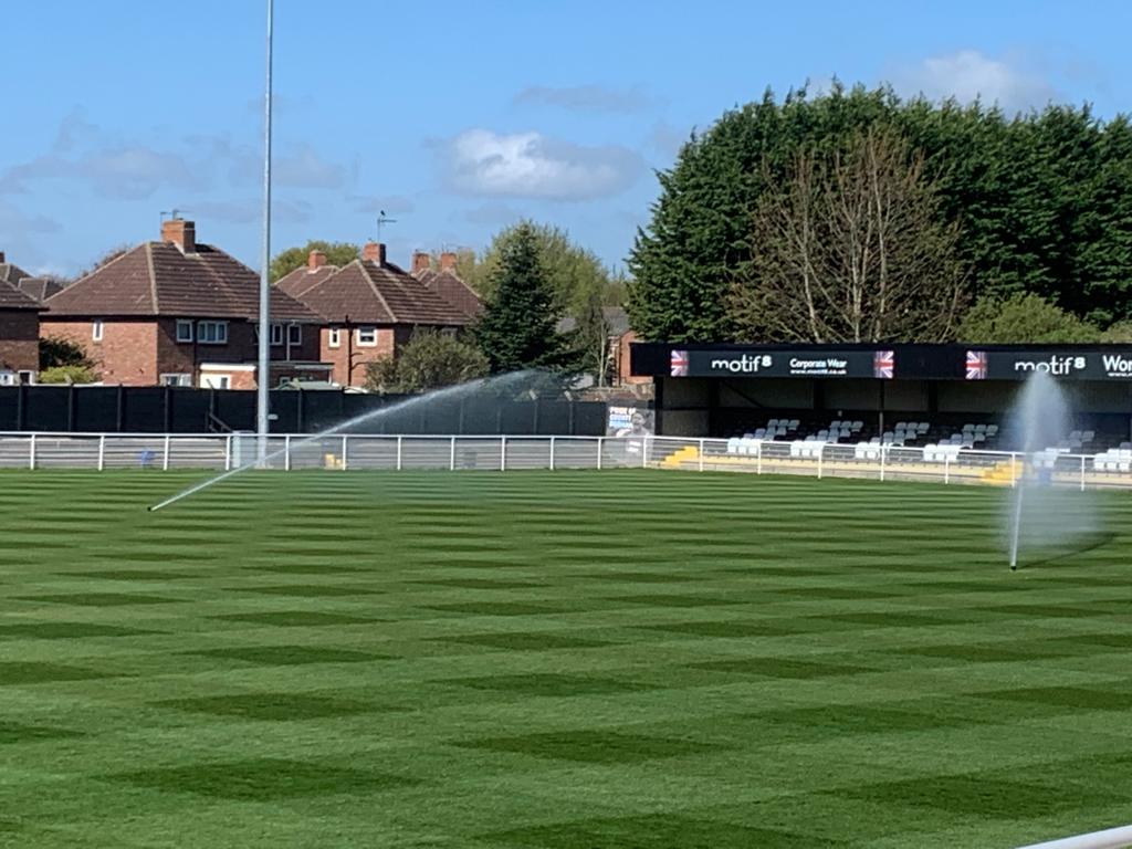 Two large sprinklers soaking a luscious green football pitch