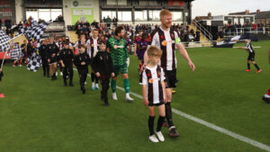 A matchday mascot leads the teams out at Spennymoor Town