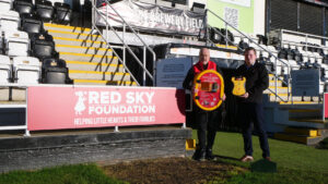 Spennymoor Town Managing Director Ian Geldard accepts the AED donation from Red Sky Foundation's Neil Parkin